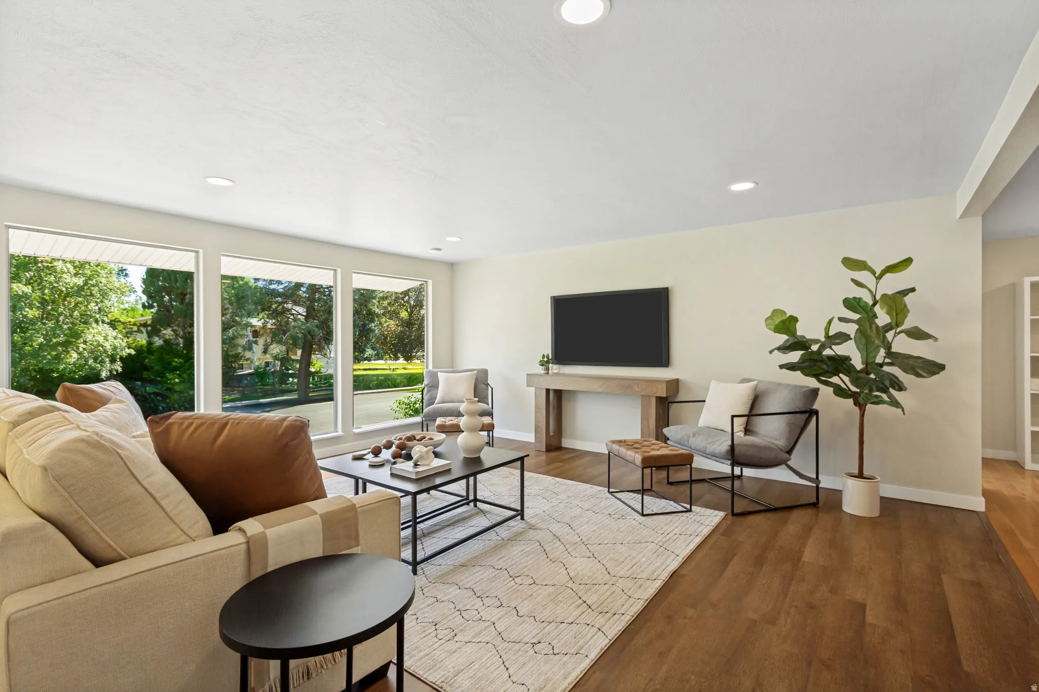 Expansive living area featuring large picture windows, recessed lighting, wood-finish flooring.