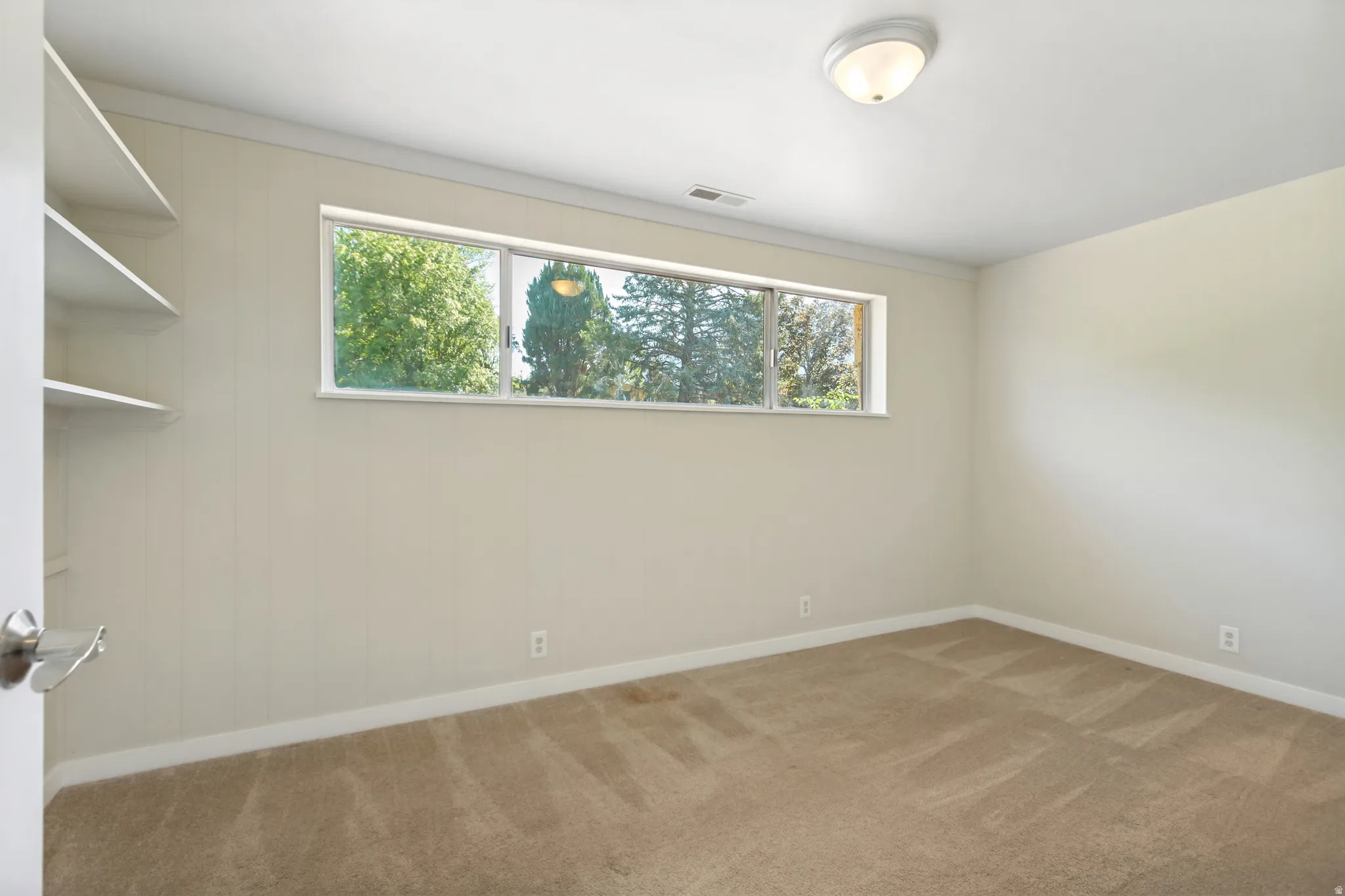 Bedroom #3 featuring neutral wall paneling, built-in shelving, and a large window