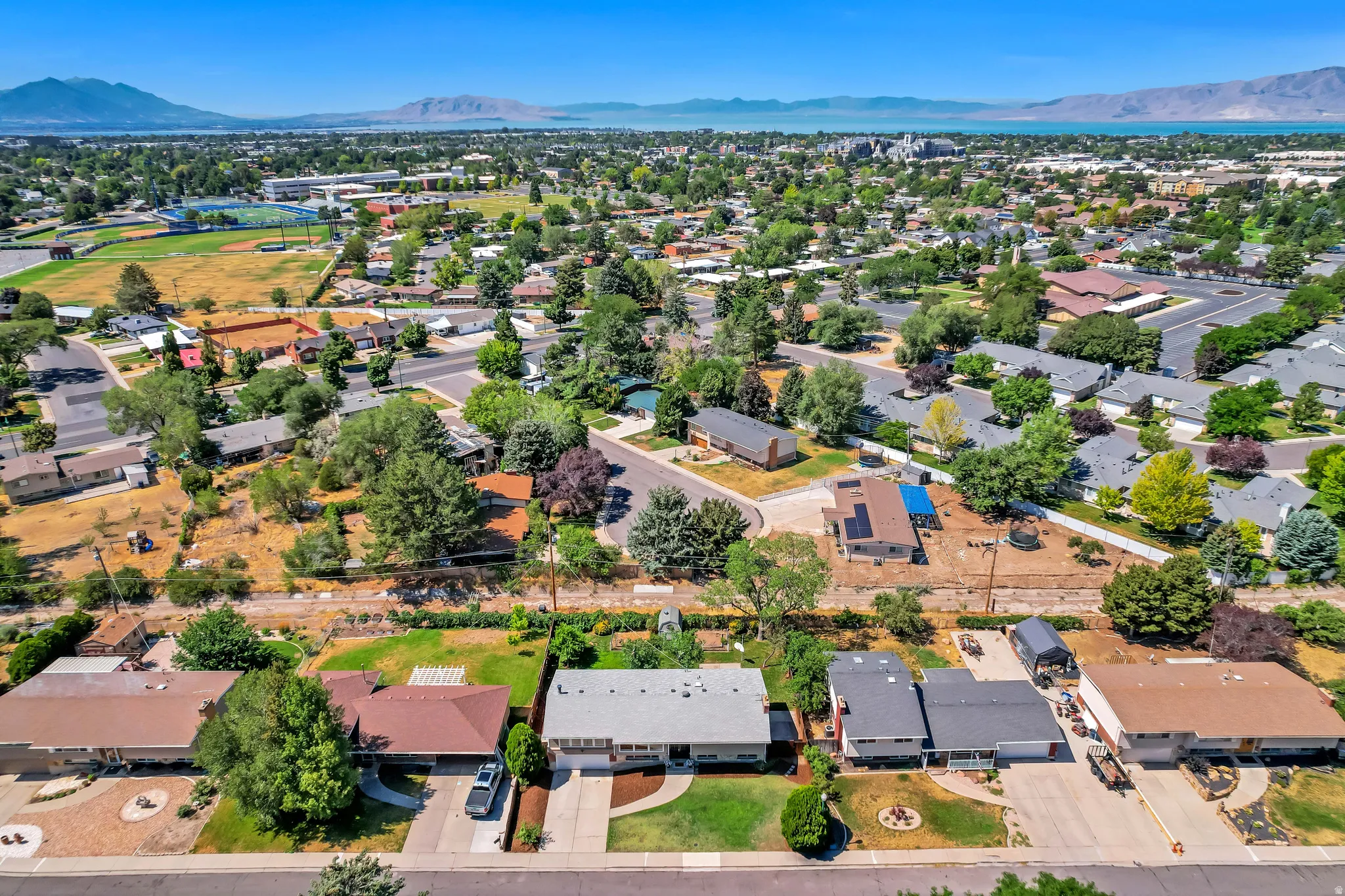 Suburban neighborhood featuring varied residential architecture, mature landscaping, and clear skies