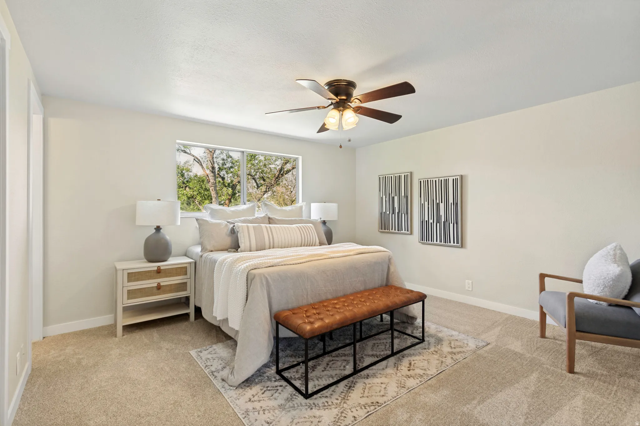 Primary Bedroom featuring neutral carpeting, a ceiling fan with integrated lighting, and a large window overlooking natural scenery