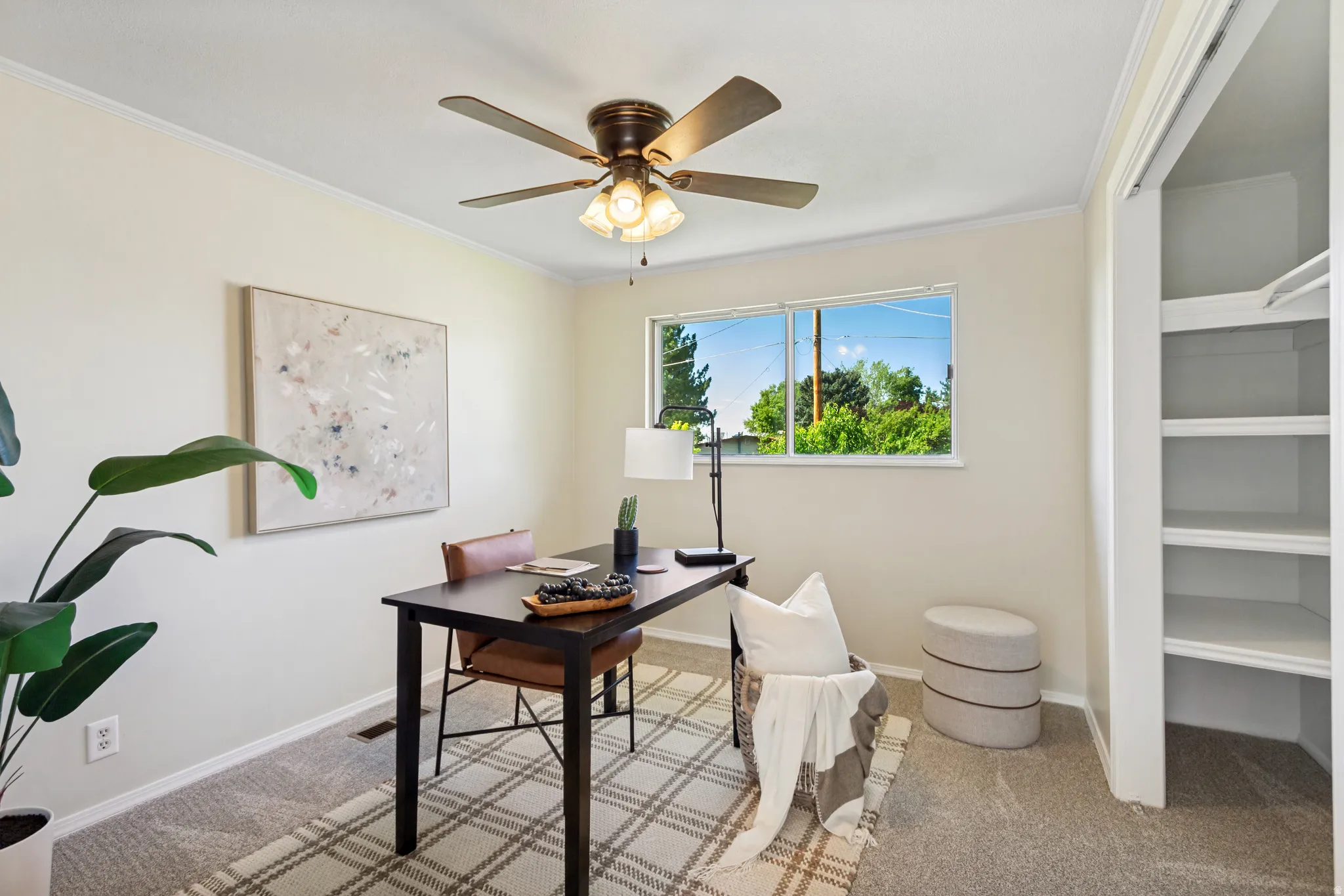 Room featuring neutral wall tones, carpet flooring, a window with exterior views, and a ceiling fan with integrated lighting