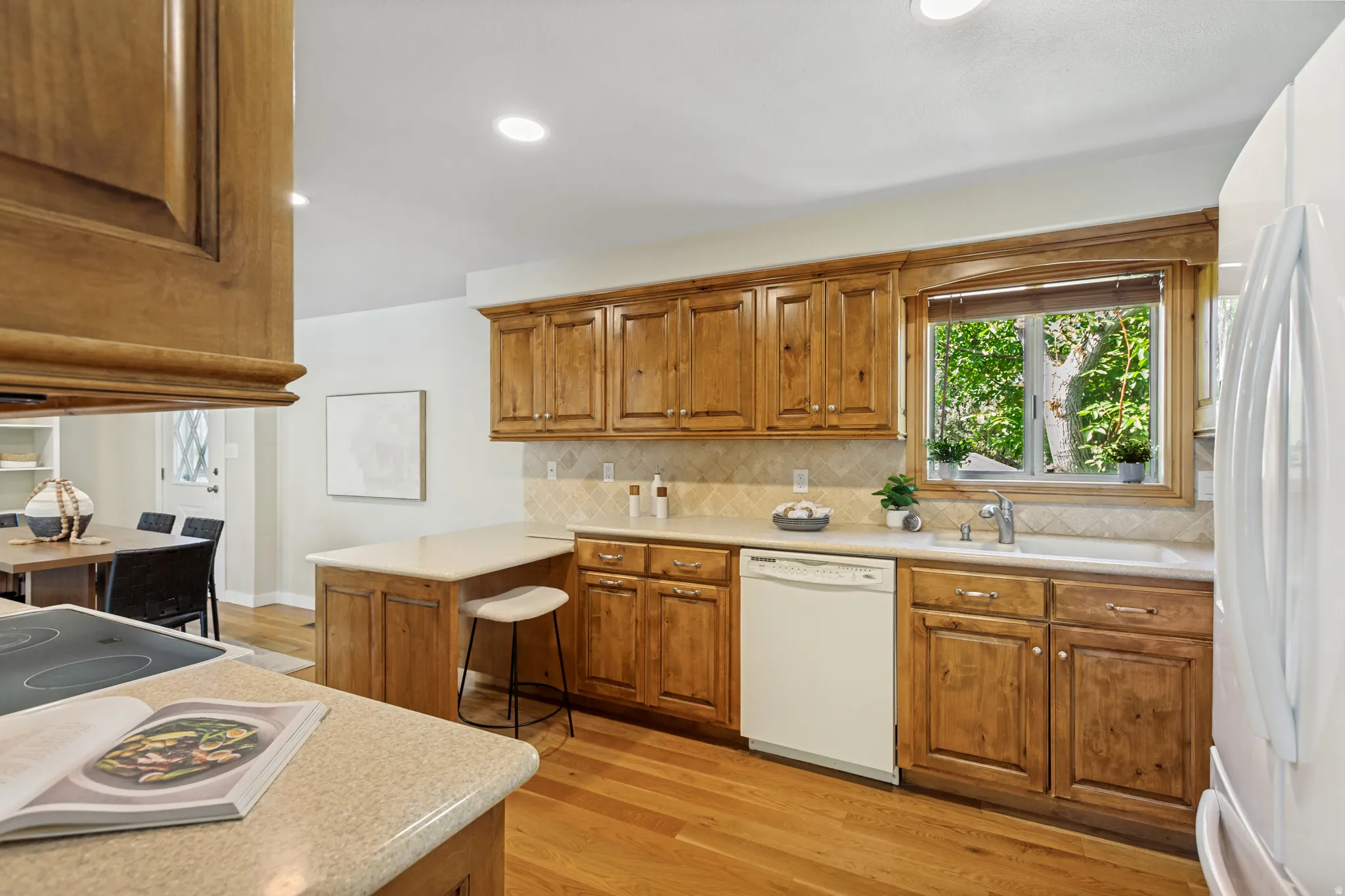 Kitchen featuring wood-finish cabinetry, light-toned countertops, and wood-finish flooring