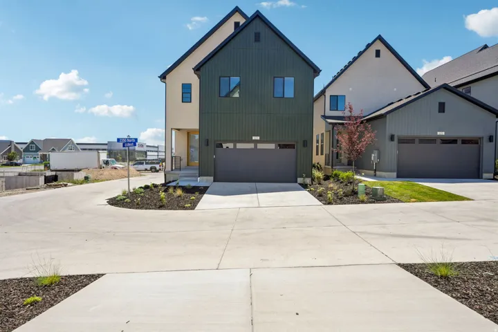 Modern architectural style featuring an olive green and beige exterior, a two-car garage, and a concrete driveway