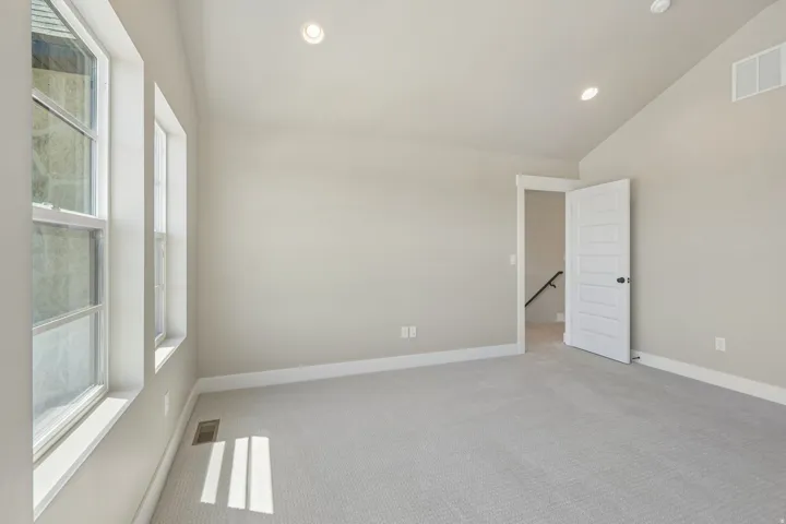 Spacious room featuring light gray carpeting, neutral wall finishes, multiple windows, recessed lighting, and white trim