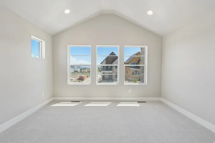 Room featuring an elevated ceiling, recessed lighting, four windows, and neutral carpeting