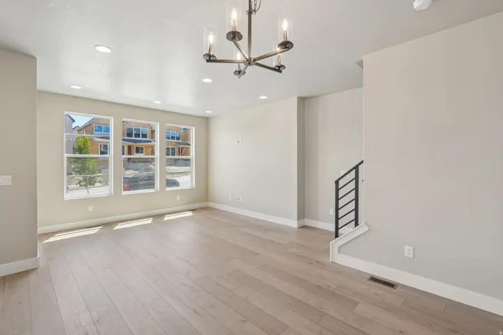 Spacious room featuring light wood-finish flooring, recessed lighting, and a modern chandelier