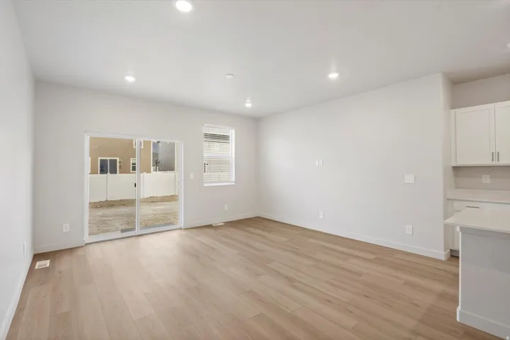 Bright open-concept living area featuring wood-finish flooring, recessed lighting, and a sliding glass door to the exterior
