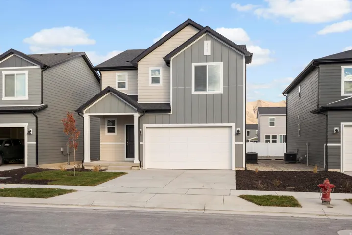 Contemporary two-story exterior featuring a two-tone gray facade, contrasting black trim, covered entry porch, and an attached two-car garage