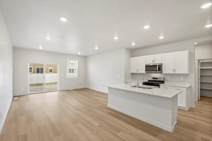 Contemporary kitchen featuring white cabinetry, a kitchen island with sink, stainless steel appliances, and light-toned countertops