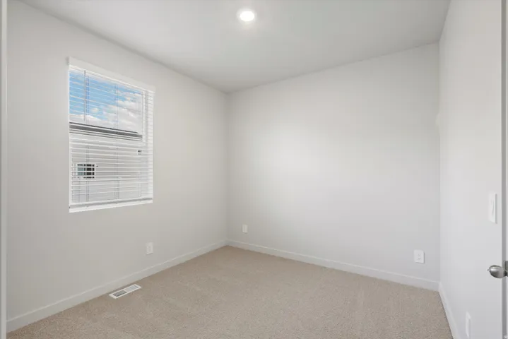 Neutral-toned room featuring a single window with blinds, recessed ceiling lighting, and light-colored carpet flooring