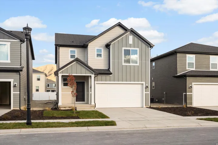 Modern two-story residence featuring a two-tone facade, attached garage, covered front porch, and black asphalt shingle roofing