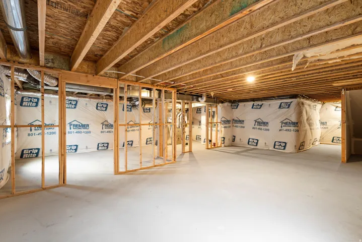 Unfinished basement featuring exposed wood joists, framed walls, and concrete flooring