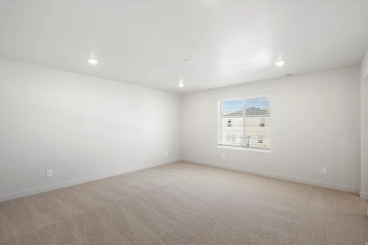 Spacious room featuring neutral carpet flooring, white painted walls, and recessed lighting