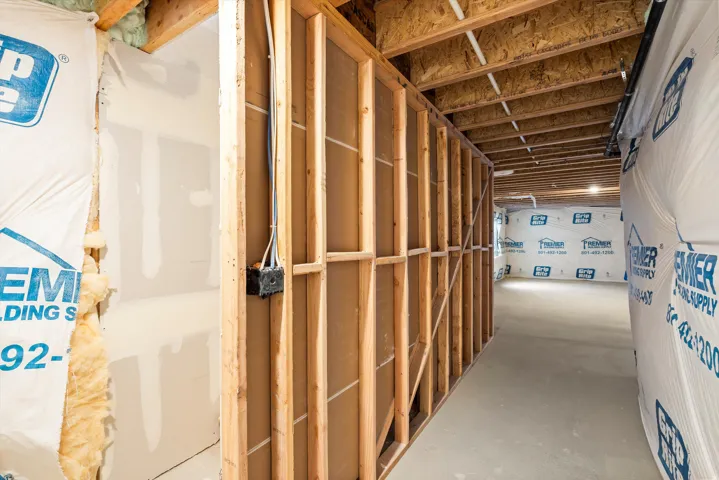 Unfinished lower level featuring wood framing, exposed ceiling joists, and concrete flooring