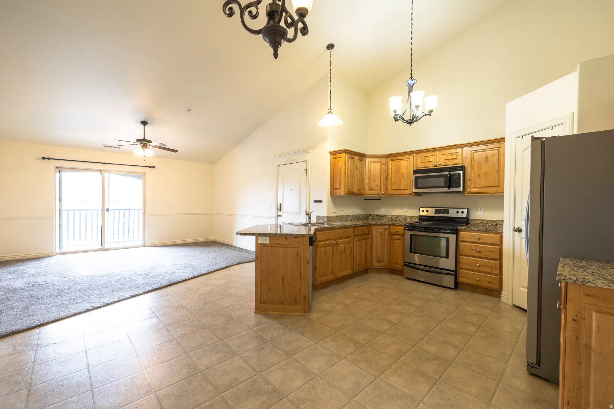 Open-concept living space featuring a kitchen with wood cabinetry, granite-finish countertops, and stainless steel appliances