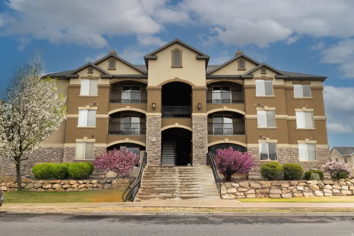 Multi-story residential building featuring a stucco and stone veneer exterior