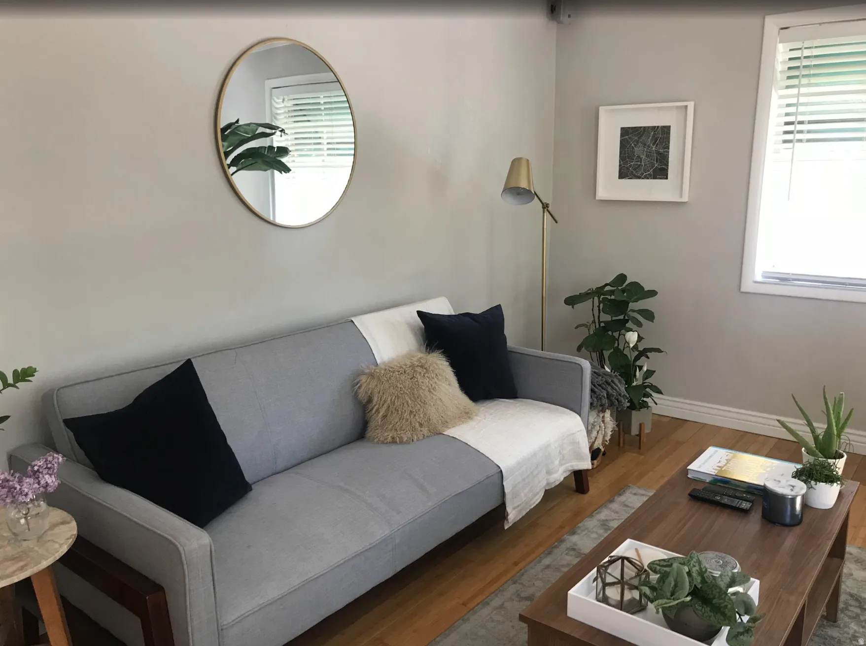Living area featuring light gray walls, wood-finish flooring, white baseboards, and a window with blinds