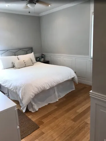 Spacious room featuring wood-finish flooring, white paneling, and crown molding
