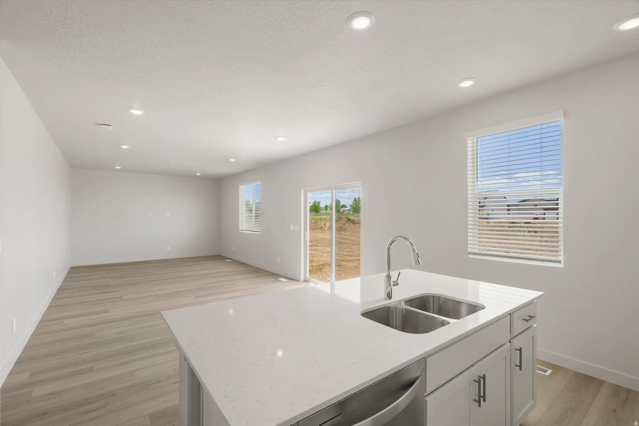 Kitchen island with an undermount double basin sink, high-arc faucet, and white countertop