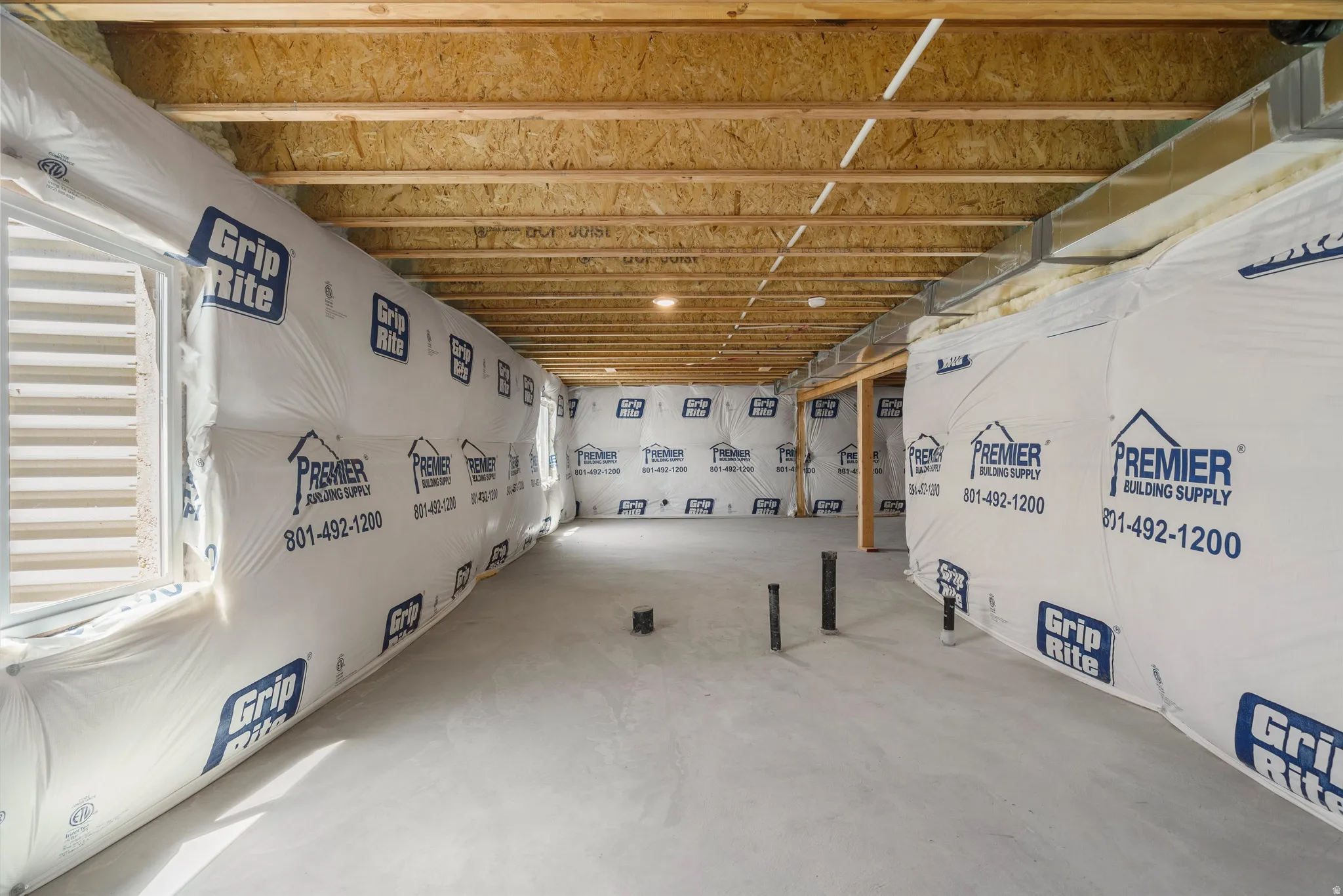 Unfinished basement with exposed ceiling joists and subflooring
