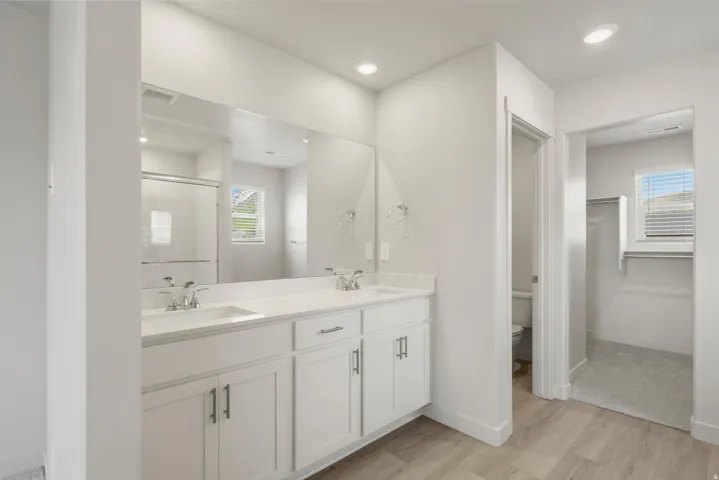 Double vanity with white cabinetry, integrated sinks, and chrome faucets