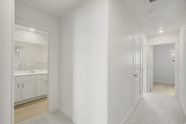 Hallway featuring light gray carpeting, white painted walls, and recessed lighting