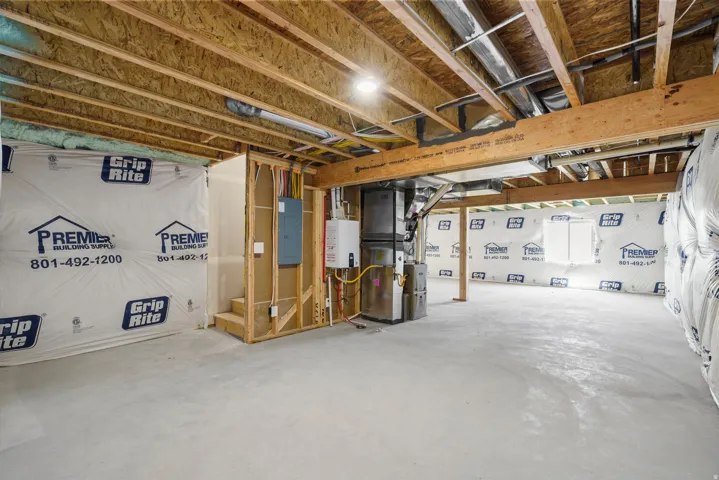 Unfinished basement with exposed ceiling joists, concrete flooring, and an exposed utility area featuring mechanical systems