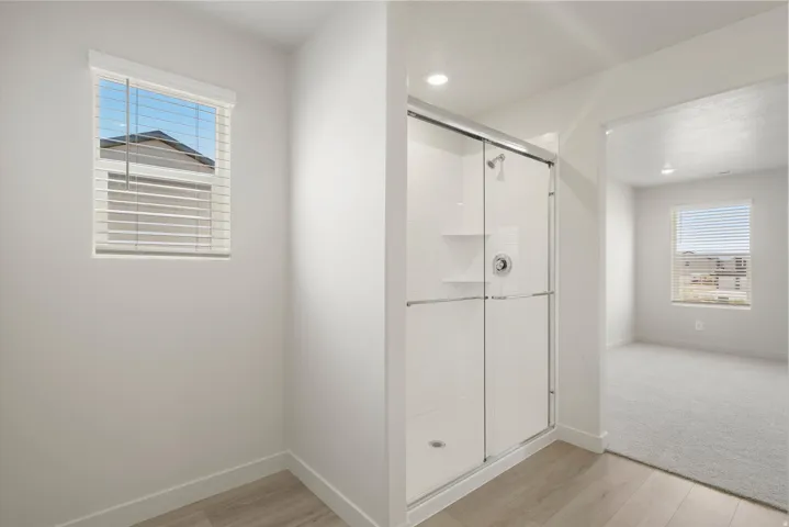 Shower enclosure featuring a sliding glass door and integrated shelving