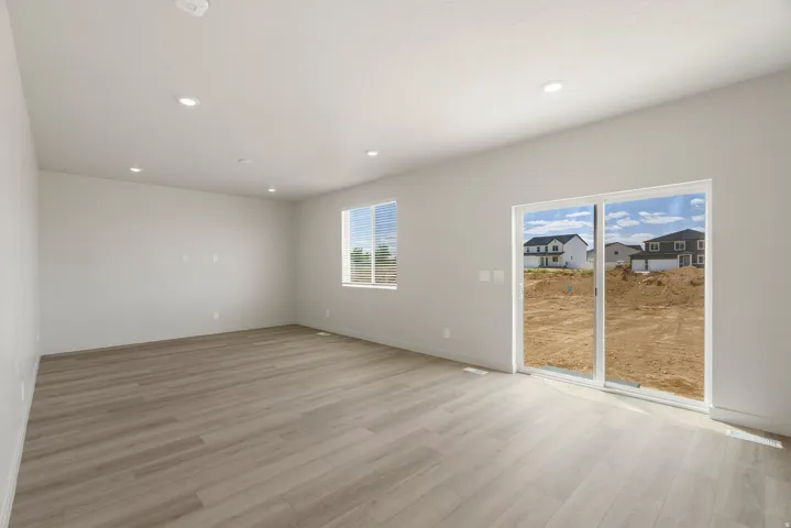 Spacious room featuring wood-finish flooring, recessed lighting, and a large sliding glass door