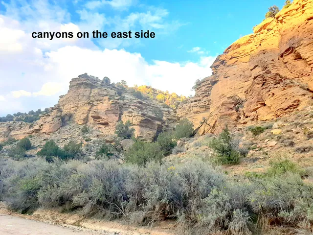 Natural canyon formations featuring stratified rock faces, rugged terrain, and scattered desert vegetation