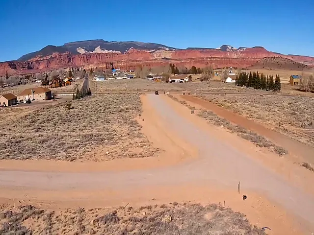 Expansive undeveloped land parcel with a dirt road, surrounded by sparse vegetation and distant mountain ranges