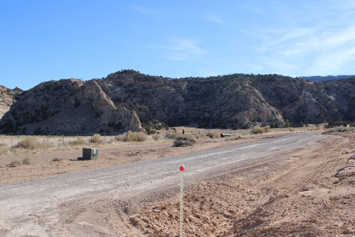 Gravel road traversing expansive desert landscape with rugged mountain backdrop