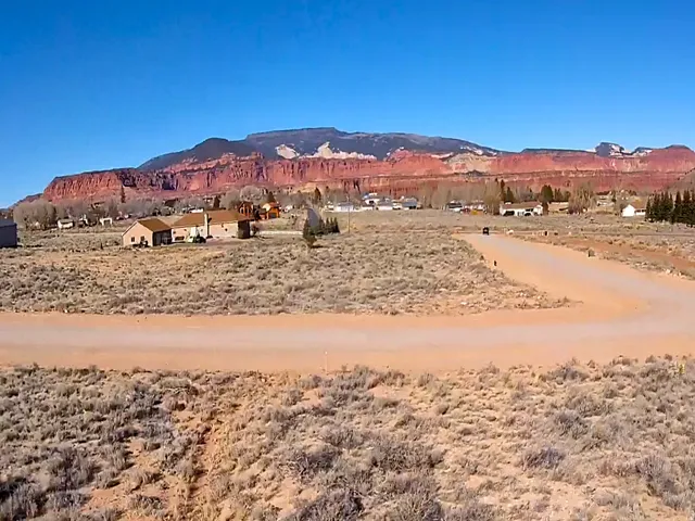 Expansive undeveloped parcel featuring a dirt road, sparse natural vegetation, and a clear blue sky