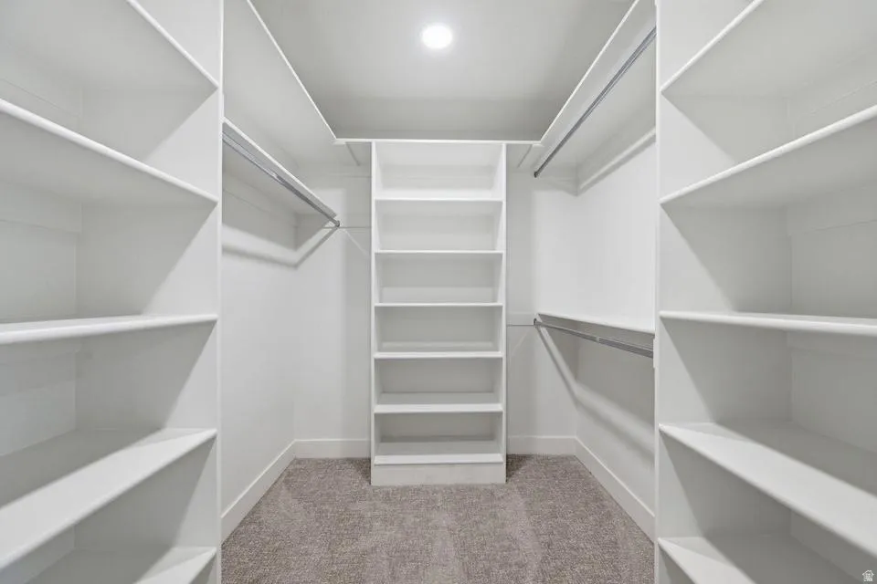 Walk-in closet featuring built-in shelving, multiple hanging rods, recessed ceiling lighting, and carpet flooring
