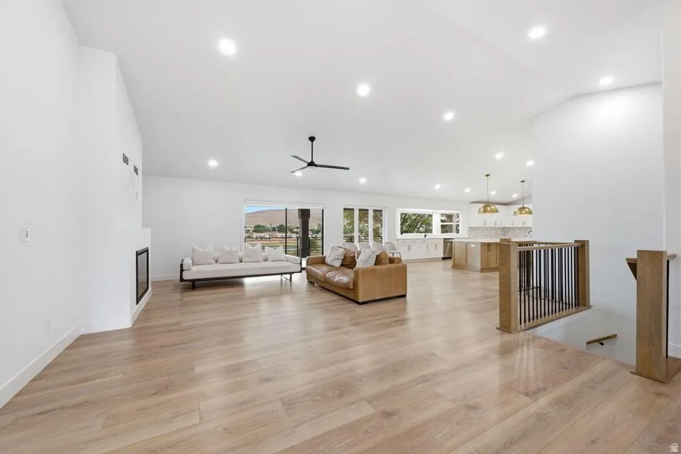 Spacious living area featuring light wood-finish flooring, a contemporary fireplace, and recessed lighting