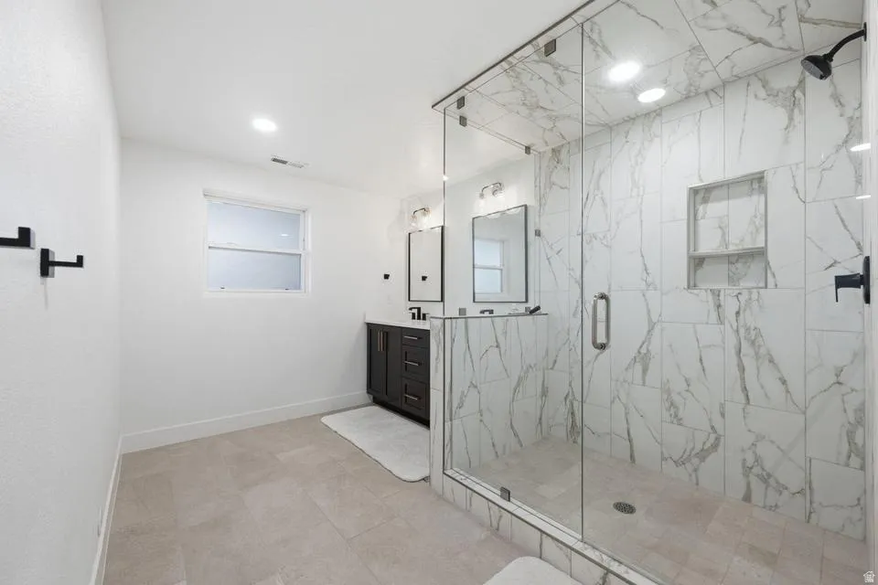 Spacious bathroom featuring a glass-enclosed shower with white marble-look tile, a built-in shower niche, and matte black fixtures