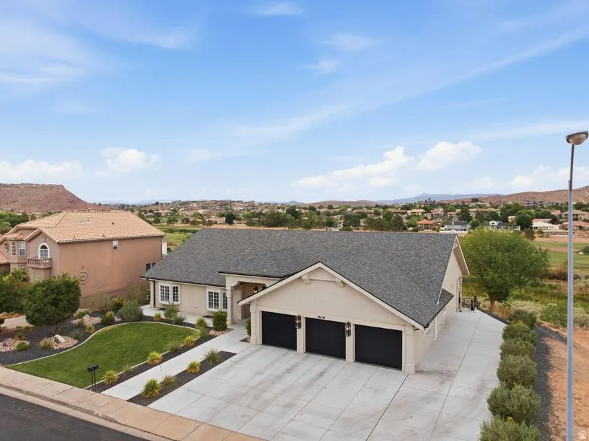 Contemporary ranch-style residence featuring a pale stucco exterior and a dark shingle roof
