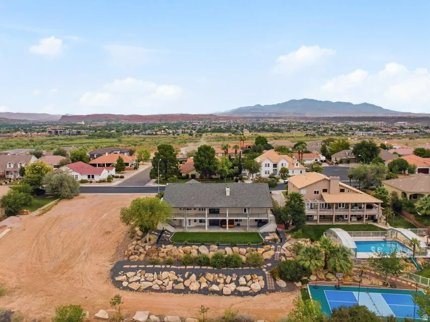 Expansive property featuring a multi-level residence with covered balconies, a terraced rock garden, and a sport court