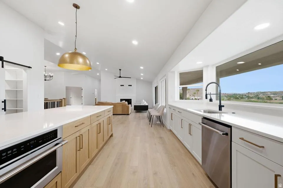 Open-concept kitchen featuring an expansive island with an integrated microwave, white countertops, and wood-finish flooring