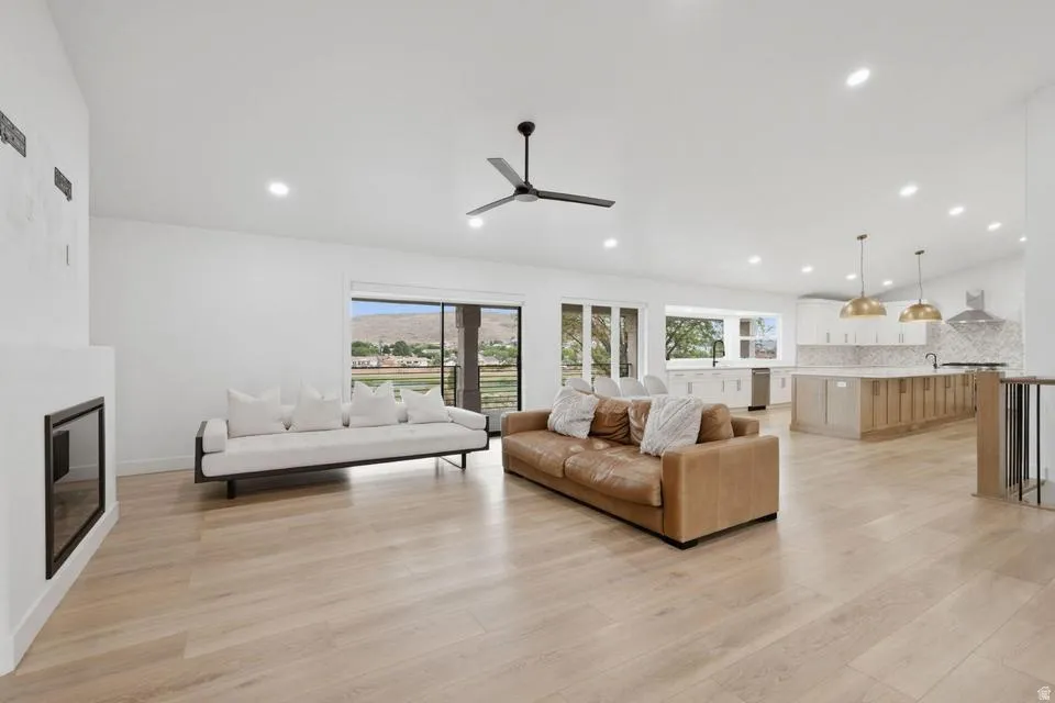 Spacious open-concept living area featuring light wood-finish flooring and a modern linear fireplace
