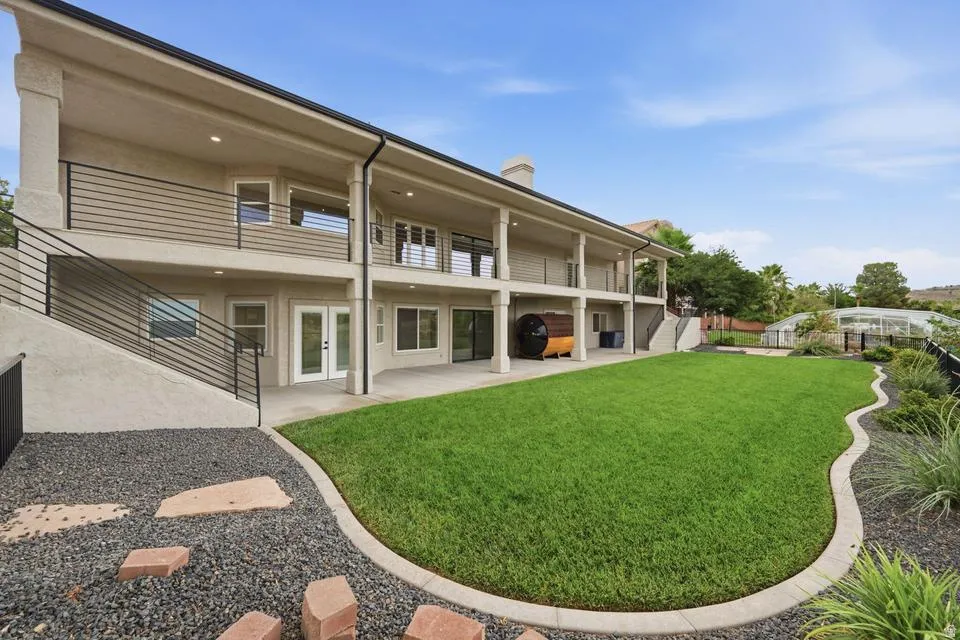 Expansive rear exterior featuring a manicured lawn, a two-story covered patio, and a lower-level concrete patio