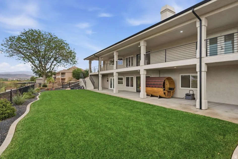 Expansive backyard featuring a manicured lawn, tiered landscaping, and mature trees
