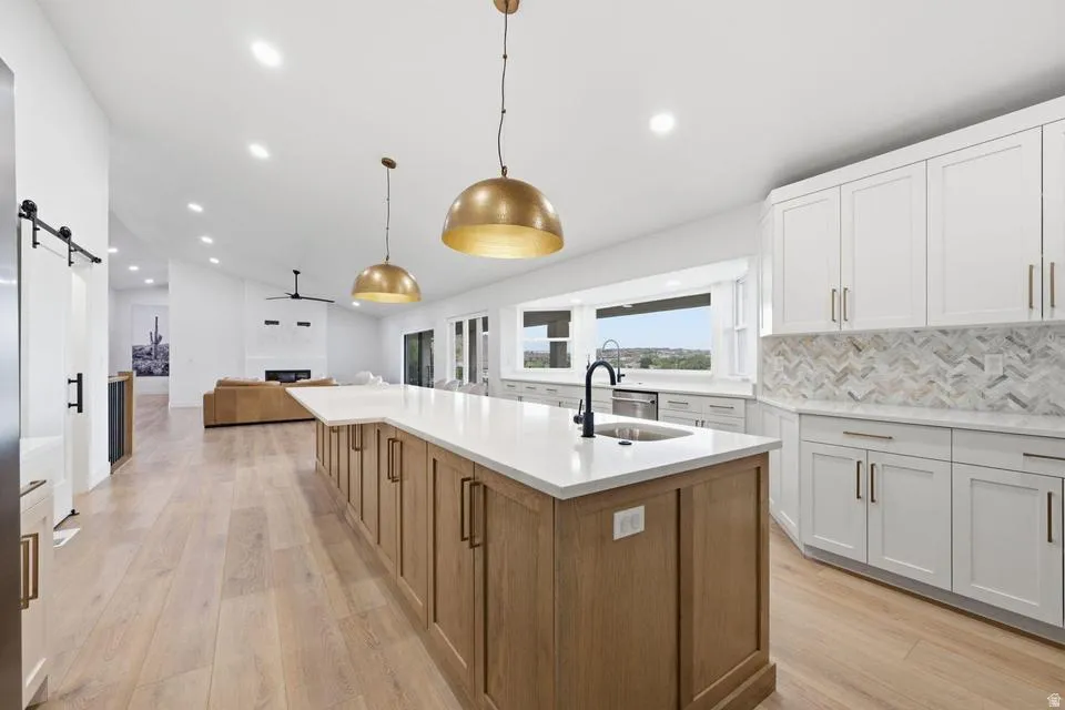 Spacious kitchen featuring a large central island with light wood-finish cabinetry, white countertops, and dual brass pendant lights