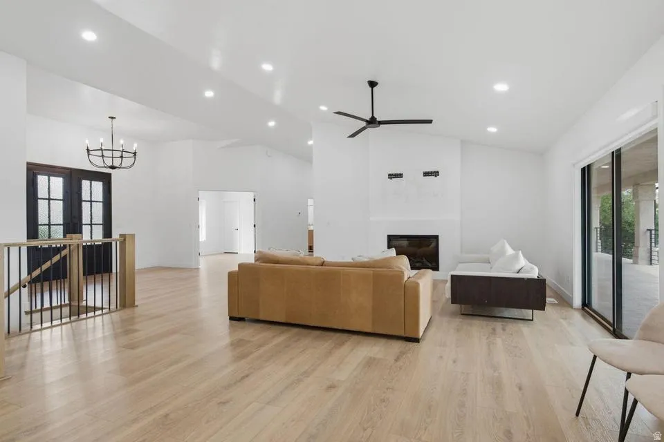 Spacious living area featuring light wood-finish flooring, a contemporary fireplace, and a black ceiling fan
