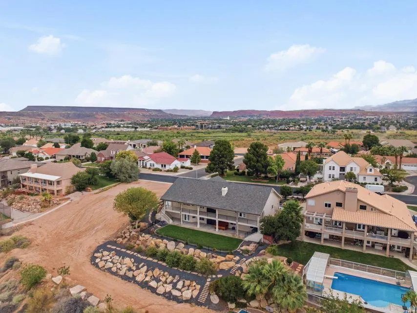 Expansive property featuring a large backyard with a manicured lawn, a rock-lined pathway, mature trees, and a mountain backdrop