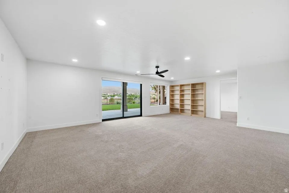 Spacious interior room featuring light-colored carpeting, white walls, and recessed lighting