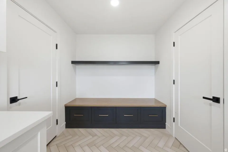 Entryway featuring a built-in bench with dark cabinetry, a light wood-finish top, and a floating shelf above