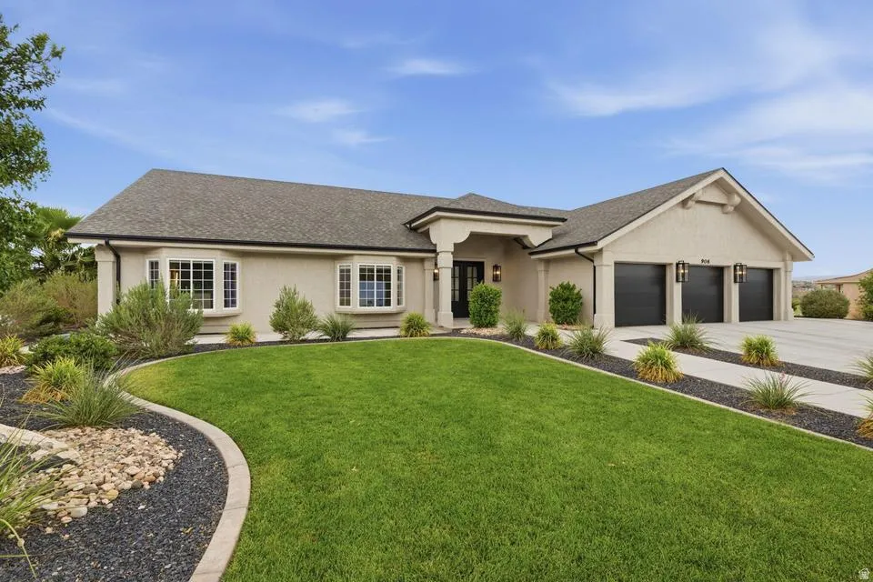 Stucco exterior featuring bay windows, a three-car garage, concrete driveway, and a manicured lawn