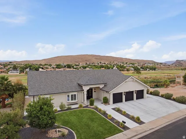 Modern stucco exterior with a three-car garage, concrete driveway, and front lawn landscaping