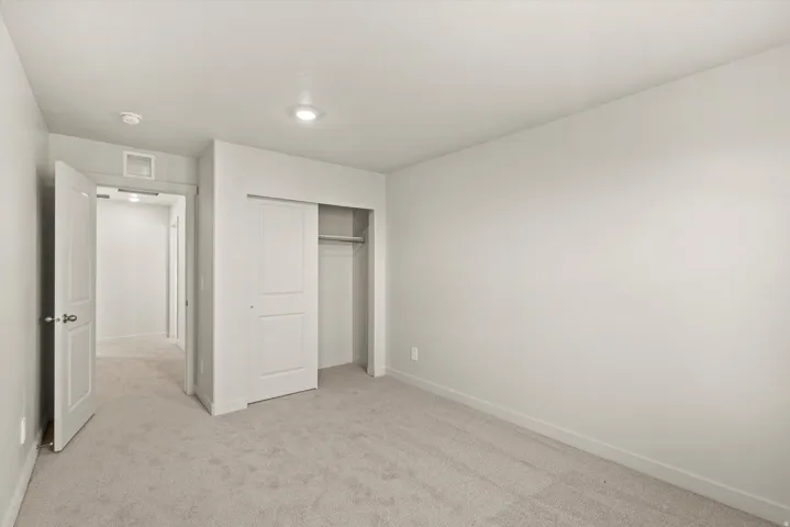 Neutral-toned bedroom featuring wall-to-wall carpeting, recessed lighting, and a sliding closet door